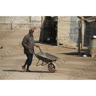 Man Pushing a Wheelbarrow along a Street in Massawa