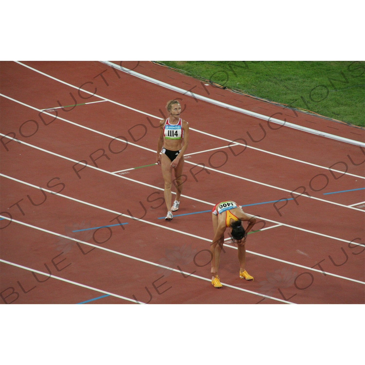 Athletes at the end of a Women's 3,000 Metre Steeplechase Heat in the Bird's Nest/National Stadium (Niaochao/Guojia Tiyuchang) in the Olympic Park in Beijing