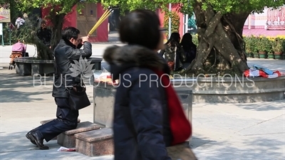 Man Burning Incense and Praying at Po Lin Monastery on Lantau Island