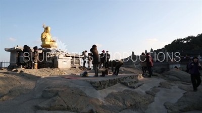 People Praying in front of a Gold Buddha Statue at Haedong Yonggung Temple (Haedong Yonggungsa) in Busan