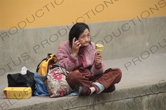 Woman Spinning a Prayer Wheel and Talking on a Mobile Phone beside West Lake (Xihu) in Hangzhou