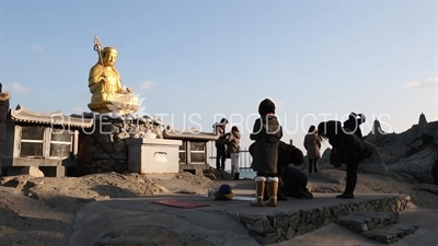 People Praying in front of Gold Buddha Statue at Haedong Yonggung Temple (Haedong Yonggungsa) in Busan