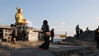 People Praying in front of Gold Buddha Statue at Haedong Yonggung Temple (Haedong Yonggungsa) in Busan