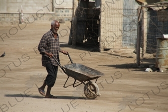 Man Pushing a Wheelbarrow along a Street in Massawa