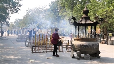 Woman Praying and Burning Incense in a Censer at Po Lin Monastery on Lantau Island